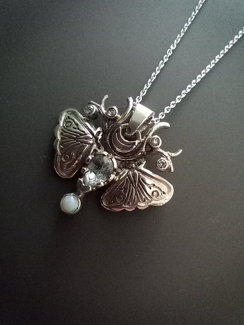 Sterling Silver Moth Pendant featuring Aquamarine, white opal and cubic zirconia. Detailed moth wings are made up of two months meeting at top where deer antlers are in place of antennas.