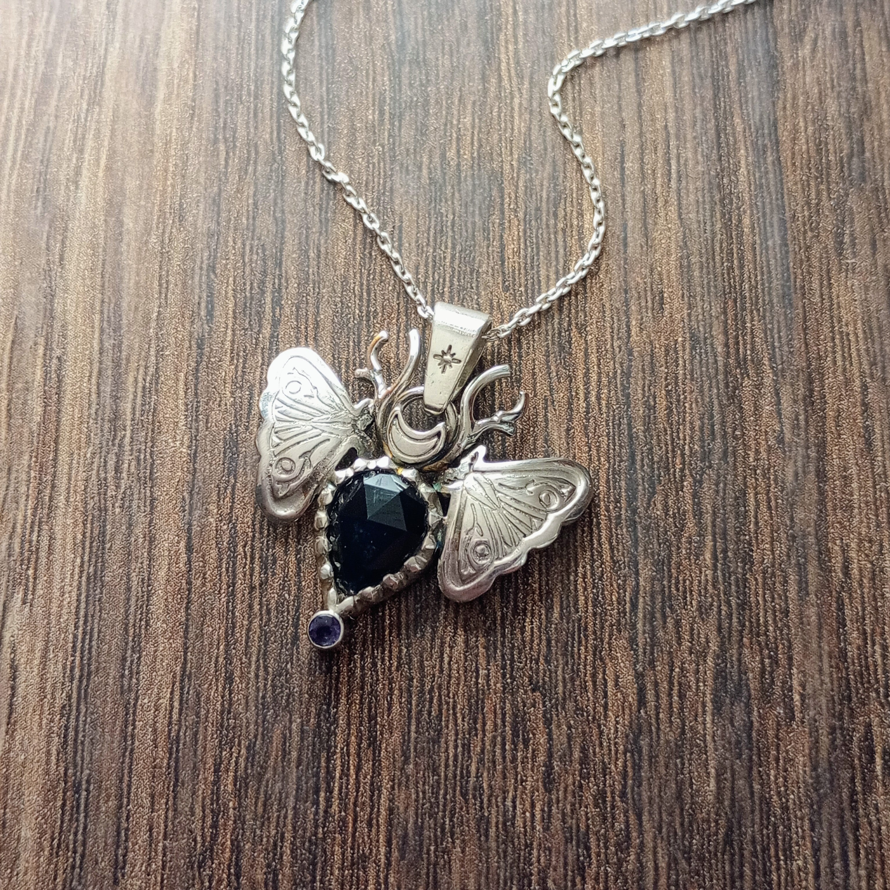 Sterling Silver Moth Pendant featuring Rose cut dark blue sapphire and iolite. Detailed moth wings are made up of two months meeting at top where deer antlers are in place of antennas.